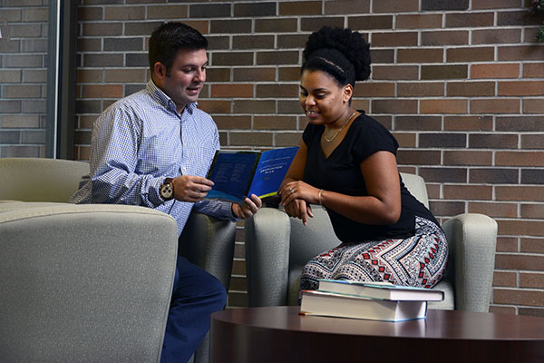 two employees reviewing a work policy handbook