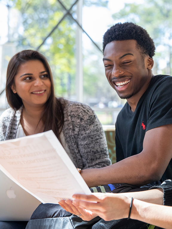 Three smiling UWF students studying together