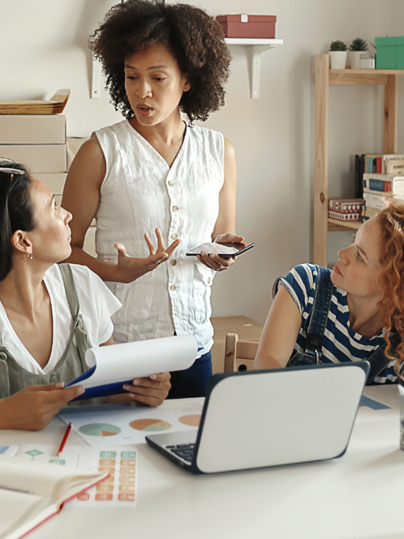 Three entrepreneur professionals conversing with two sitting at a table.