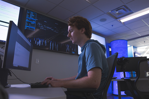 Student working at a computer in a cybersecurity classroom lab.