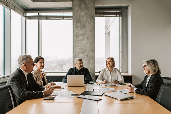 Five business executives seated at an indoor table for a meeting.