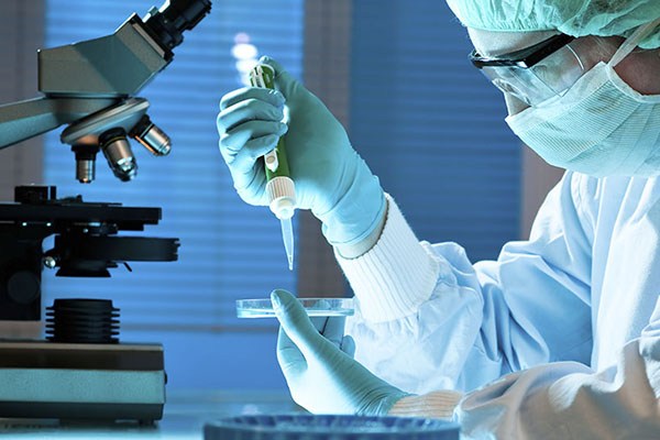 Technician working in a laboratory while wearing lab protection gear.
