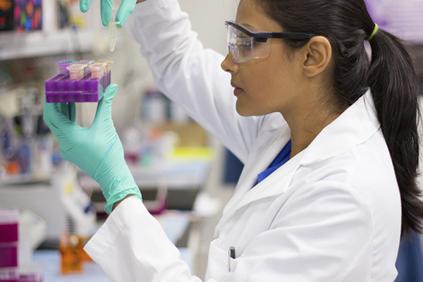 Public health worker in the lab wearing eye protection and lab coat.