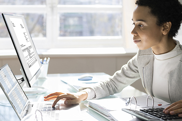 Healthcare professional in professional attire using a computer in an office setting.