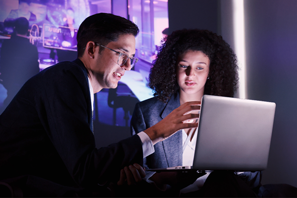 Two business professionals collaborating on a laptop indoors.