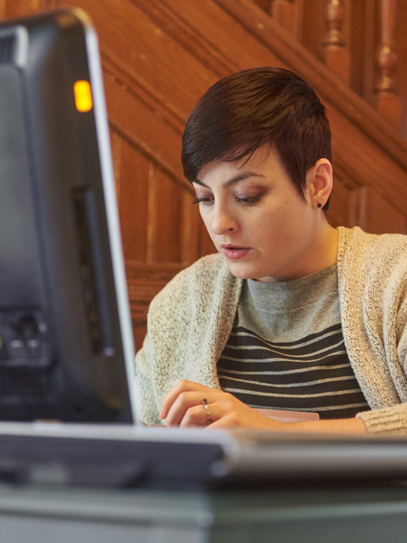 UWF graduate seated in front of a computer in the child mental health center.	