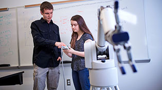 two students working with a robotic arm