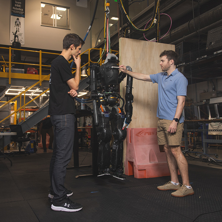 Two graduate research students examining a robot in a robotics lab.