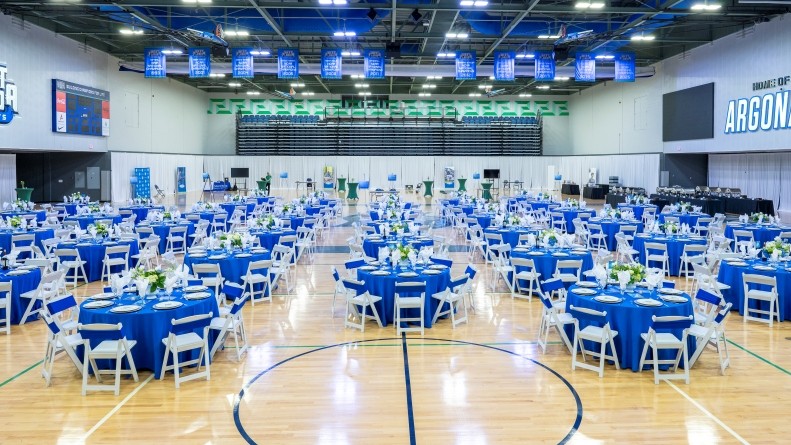Banquet Rounds covered in blue linen for a large elegant event set up in the UWF Field House