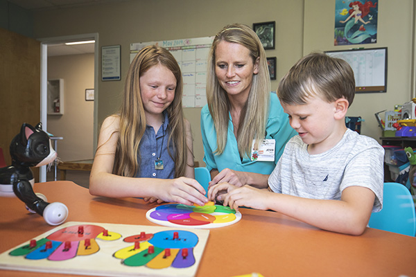 applied behavior analysis student working with two children at a table