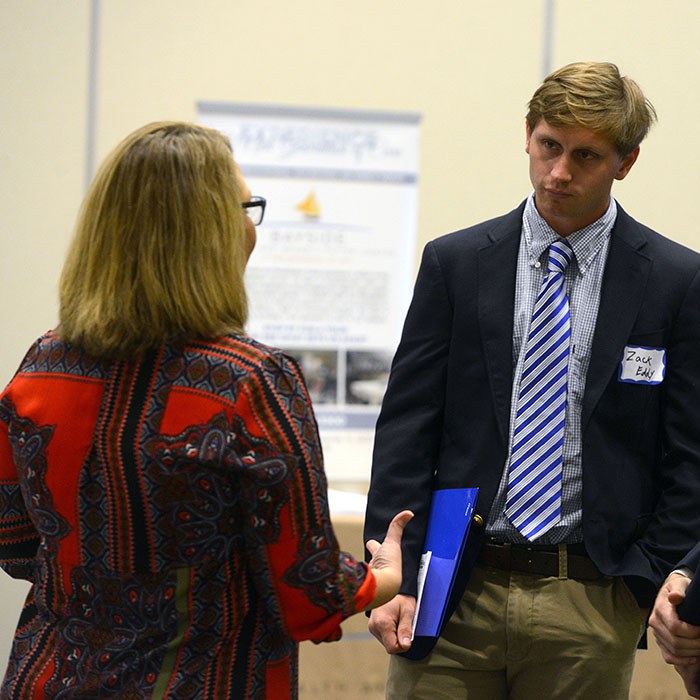 a communication student speaks with an employer at a career fair