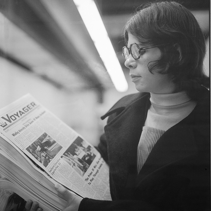 uwf student holding a stack of paper copies of the voyager