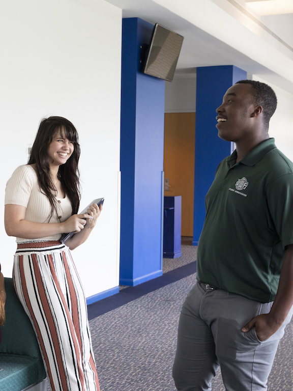 two students having a conversation in a hall on campus