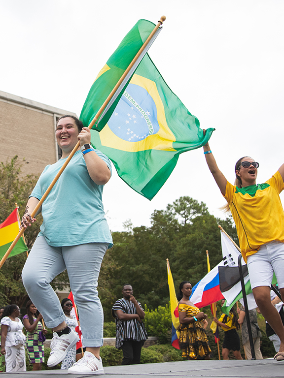 Student waving a brazilian flag onstage	