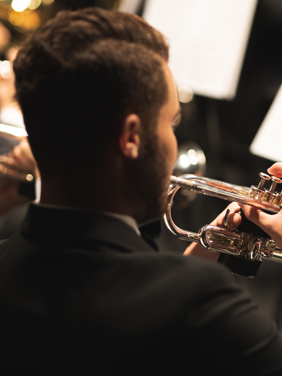 a male student playing trumpet in the orchestra