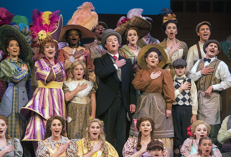 cast of music man on stage singing a song
