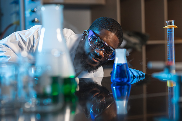 chemistry student examining beakers filled with blue and green colored liquids