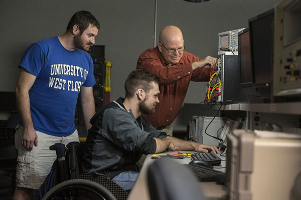 electrical engineering students and faculty working on electronics in a lab