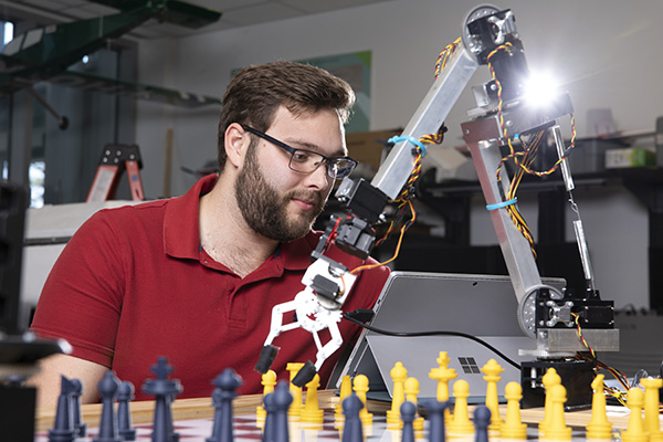 engineering student examining a chess playing robot