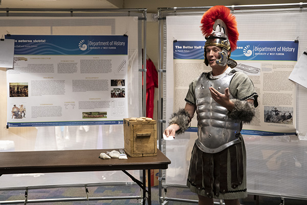 student presenting a history project while wearing a replica ancient suit of armor