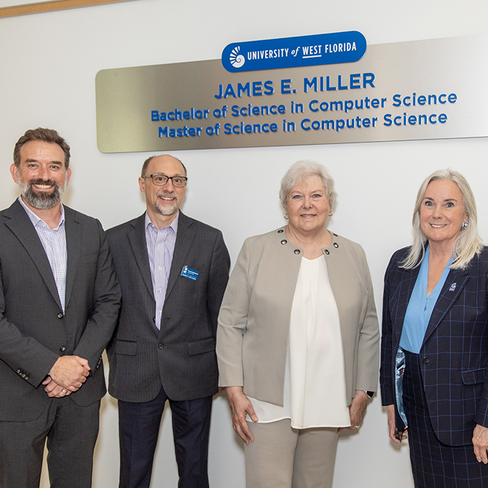 UWF President Martha Saunders, Provost Jaromy Kuhl, and Department of Computer Science Chair Dr. Thomas Reichherzer with a member of James Miller’s family in front of a UWF donor signage that states “James E. Miller” above “Bachelor of Science in Computer Science” which is above “Master of Science in Computer Science” on the signage.