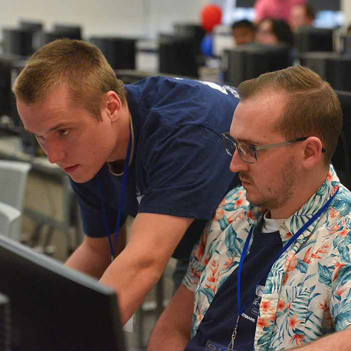 Two UWF computer science students working at a computer during a computer science competition.