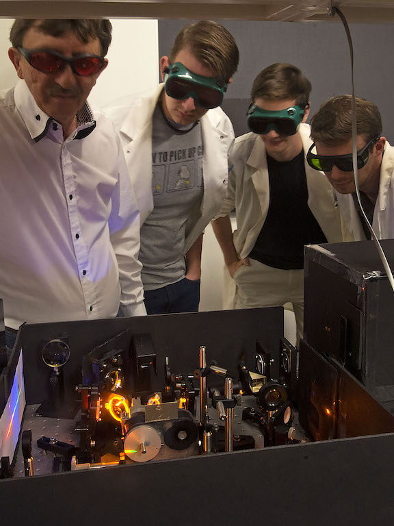 a professor and three students working in the laser lab