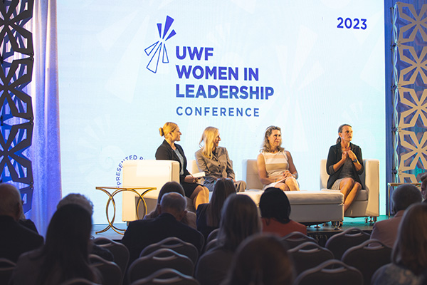 Four speaker panel in front of the crowd at the 2023 UWF Women in Leadership Conference.