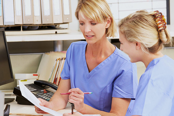 two nurses reviewing paperwork at a desk