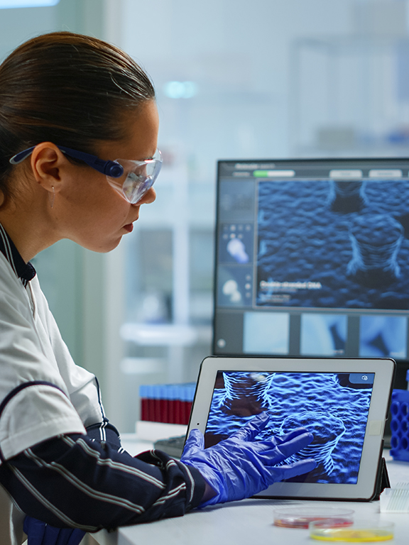 Scientist using digital tablet analysing virus evolution, treatment development in medical research laboratory.
