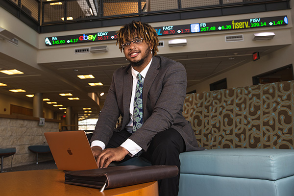 UWF student in suit and tie attire working on a laptop.